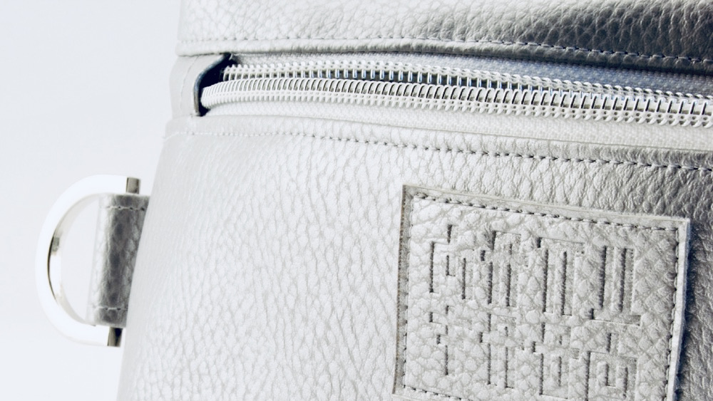 Nahaufnahme von Manufabo Logo und Beschlägen auf einer silbernen, metallischen Cosmetic Bag