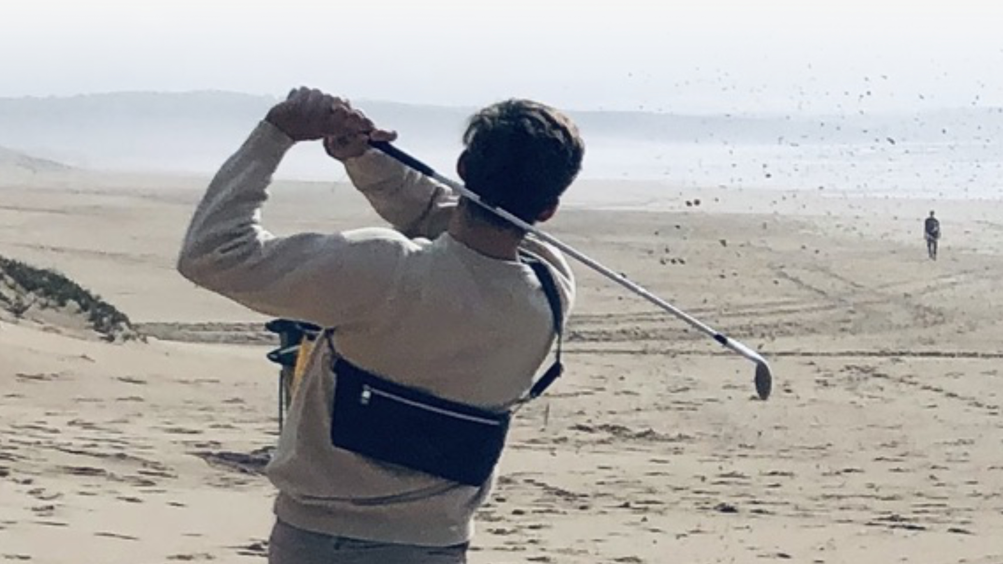 Golfer mit Manufabo Belt Bag schlägt am Strand ab — die Taschen fliegen aus den Regalen, ab in den Sonnenuntergang