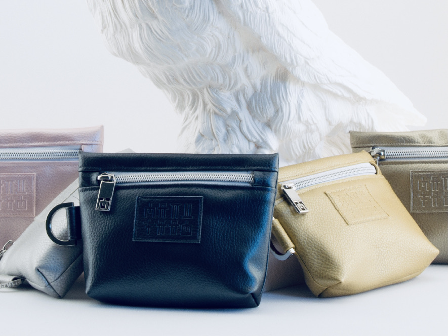 Manufabo Mini Bags in verschiedenen Metallic-Tönen vor der Statue eines weißen Raben